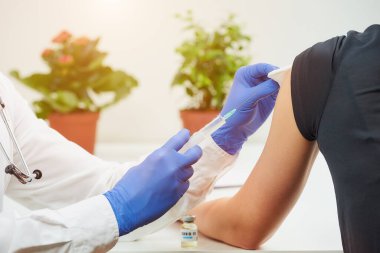 Tek kullanımlık tıbbi eldiven giyen bir doktor hastasına koronavirüs aşısı enjekte ediyor. Bir hastanede COVID-19 aşısı kullanan bulaşıcı bir doktor..