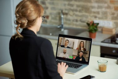 Bir kadının omzunda dizüstü bilgisayar görüntüsü. Stüdyosundaki bilgisayarda uzaktan çalışan bir kız. Evde online bir derste öğrencilerin cevaplarını dinleyen bir kadın profesör..