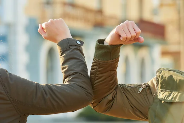 Elbow greeting to avoid the spread of coronavirus (COVID-19). A man and a young woman meet on the street with bare hands. Instead of greeting with a hug or handshake, they bump elbows instead.