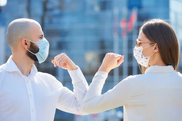 Elbow bumping. Elbow greeting to avoid the spread of coronavirus (COVID-19). Colleagues in shirts meet in the street with bare hands. Instead of greeting with a handshake or a hug, they bump elbows.