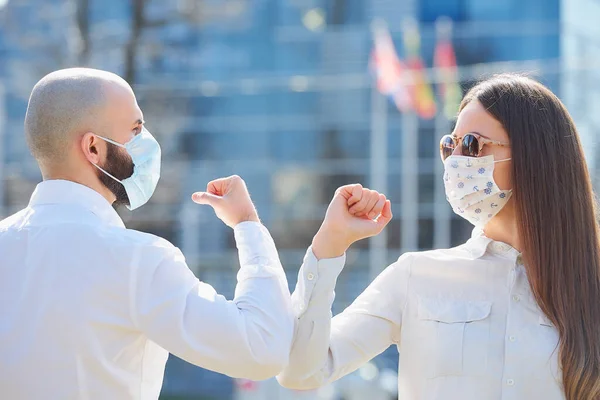 Elbow bumping. Elbow greeting to avoid the spread of coronavirus (COVID-19). A woman and a man meet in the street with bare hands. Instead of greeting with a handshake or a hug, they bump elbows