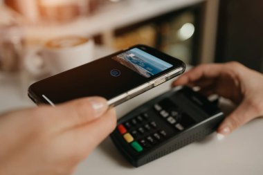 Kahvesinin parasını bir kafede parasız servis teknolojisiyle ödeyen bir kız. Kadın bir barista, bir kahve dükkanında müşteriye ödeme yapmak için bir terminali soyar..