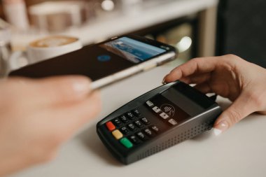 Kahvesini akıllı telefonla ödeyen bir bayan bir kafede NFC teknolojisiyle temas kuramıyor. Kadın bir barista, bir kahve dükkanında müşteriye ödeme yapmak için bir terminali soyar..