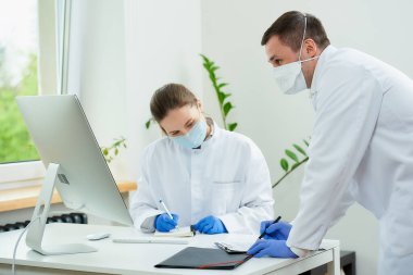 Tıbbi maskeli bir cerrah ve radyoloji uzmanı hastanede bir hastanın teşhisini tartışıyor. Masaüstü bilgisayarının önünde oturan bir kadın doktor. Yanında bir terapist oturuyor..