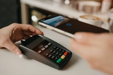 Kahvesini akıllı telefonla ödeyen bir bayan bir kafede NFC teknolojisiyle temas kuramıyor. Kadın bir barista, bir kahve dükkanında müşteriye ödeme yapmak için bir terminali soyar..