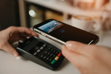 Kahvesinin parasını bir kafede parasız servis teknolojisiyle ödeyen bir kız. Kadın bir barista, bir kahve dükkanında müşteriye ödeme yapmak için bir terminali soyar..