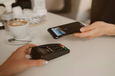 Kahvesini akıllı telefonla ödeyen bir kadın bir kafede NFC teknolojisiyle temas kuramıyor. Kadın bir barista, bir kahve dükkanında müşteriye ödeme yapmak için bir terminali soyar..