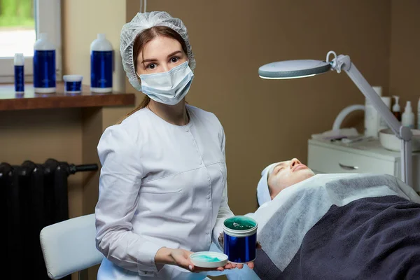 Kvindelig Kosmetolog Medicinsk Ansigtsmaske Poserer Med Hudpleje Gel Nær Patient - Stock-foto