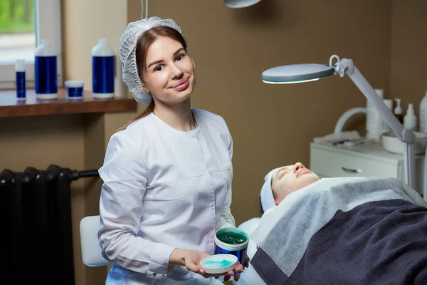 Attraktiv Kvinnlig Kosmetolog Ler Poser Med Hudvårdsgel Nära Patient Helt — Stockfoto