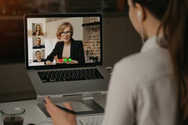 Evde bir kadının, patronuyla ve diğer iş arkadaşlarıyla dizüstü bilgisayardan yaptığı görüntüler. İş kadını web kamerası konferansında iş arkadaşlarıyla konuşuyor. İş ekibi çevrimiçi toplantı yapıyor..