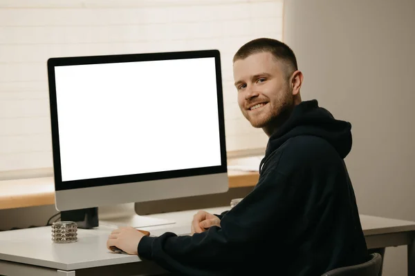 Remote work. A businessman works remotely using an all-in-one computer. A smiling fellow with a beard working from home.