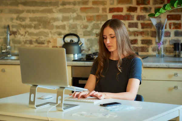 A caucasian woman working remotely on her laptop during the quarantine to avoid the spread coronavirus. A businesswoman working from home during the pandemic of COVID-19.