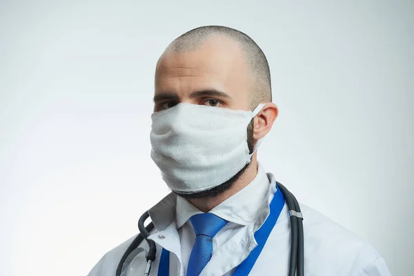 A close portrait of a doctor in a protective face mask. A doctor in a white lab coat with a stethoscope.