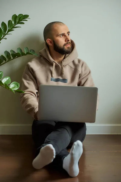 Remote work. A man with a beard working remotely on his laptop during the quarantine to avoid the spread coronavirus. A bald programmer working from home during the pandemic of COVID-19.