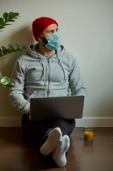 검시관 마스크를 남자가 자신의 노트북에서 원격으로 작동하는 코로나 바이러스를 피하기 — 스톡 사진