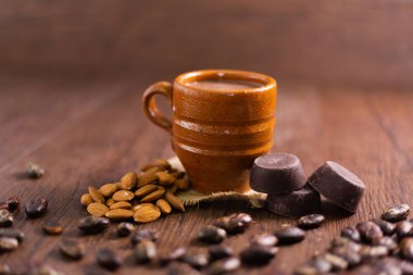 Kakao çekirdeği ve bademle çevrili bir fincan sıcak çikolata. El yapımı badem çikolatalı kil bardak.