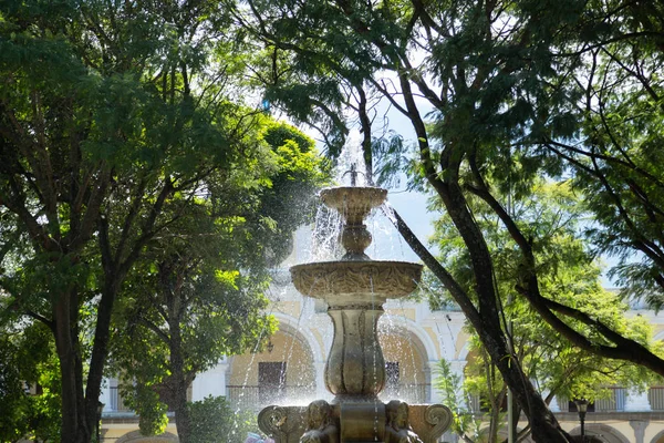 アンティグア・グアテマラのサイレンの噴水-植民地時代の都市の木々に囲まれた公園の真ん中に噴水 — ストック写真