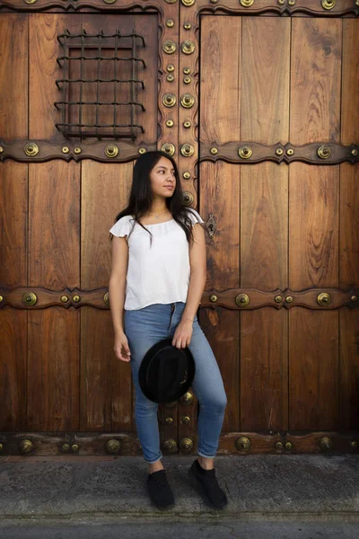 Ung latinamerikansk kvinna står vid en gammal kolonial dörr — Stockfoto