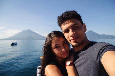 Guatemala 'daki Atitlan Gölü' nde selfie çeken maceraperest bir çift. Latin Amerika 'nın ünlü gölündeki ahşap bir iskelede duran gezginler.