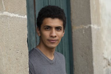 Eski bir kapıda duran genç bir İspanyol 'un portresi. Genç adam kameraya bakıp gülümsüyor.