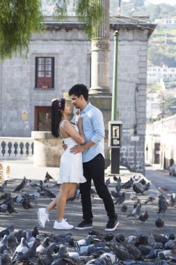 Quetzaltenango, Guatemala 'daki Central Park' ta sarılan İspanyol çift. Parkta güvercinlerle çevrili genç bir çift.