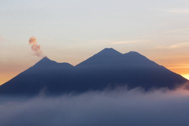 Volkan de Fuego ve volkan Acatenango 'yu çevreleyen bulutlarla gün batımı - Guatemala' daki volkanların manzarası