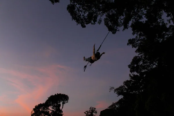 Silhouette eines Mädchens auf einer riesigen Schaukel, umgeben von Bäumen und Natur bei Sonnenuntergang - Guatemala Riesenschaukel — Stockfoto