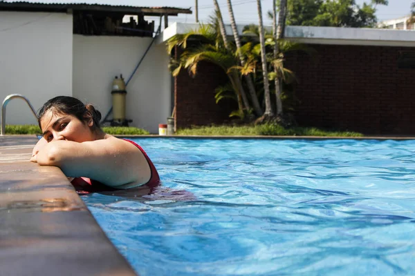 Fille courbée en maillot de bain rouge immergée dans la piscine en profitant d'une journée ensoleillée en été - Femme hispanique dans la piscine - journée de détente — Photo