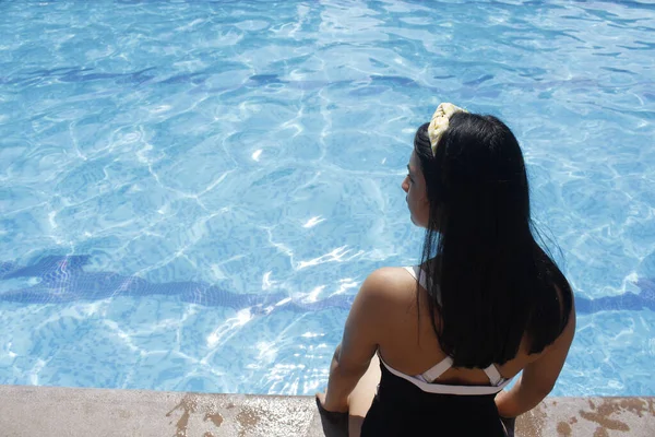 Młoda Latynoska opalająca się siedząca przy basenie w stroju kąpielowym - młoda kobieta latem na basenie — Zdjęcie stockowe