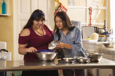 Latin kız kardeşler eğlenirken yemek pişiriyorlar - ev yapımı kurabiyeler yapan kadınlar - evde etkinlikler