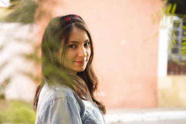 Ağaç dalları arasında kameraya bakan Latin kadının portresi.