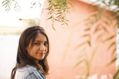 Ağaç dalları arasında kameraya bakan Latin kadının portresi.