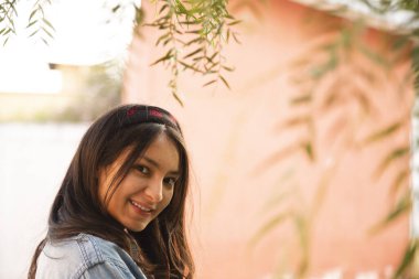 Ağaç dalları arasında kameraya bakan Latin kadının portresi.