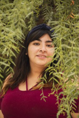 Ağaçların ortasında gülümseyen İspanyol kadın - doğal gülümsemenin ayrıntıları - Latin kadın