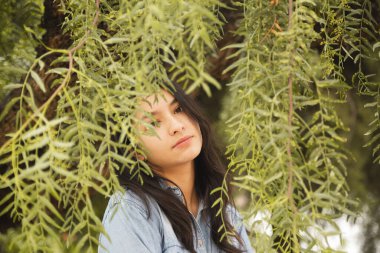 Ağaç dalları arasında kameraya bakan Latin kadının portresi.