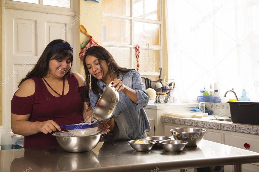 Latin sisters cooking while having fun - women making homemade cookies - activities at home