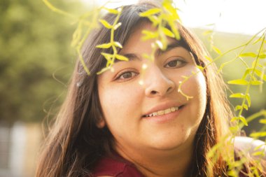 Ağaçların ortasında gülümseyen İspanyol kadın - doğal gülümsemenin ayrıntıları - Latin kadın