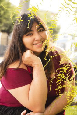 Ağaçların ortasında gülümseyen İspanyol kadın - doğal gülümsemenin ayrıntıları - Latin kadın