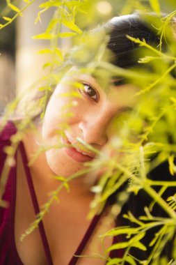 Ağaçların ortasında gülümseyen İspanyol kadın - doğal gülümsemenin ayrıntıları - Latin kadın