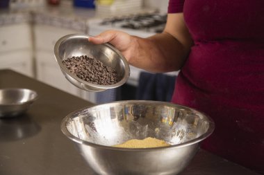 Genç bir kadının elleri kurabiye karışımına çikolata parçaları koyuyor İspanyol kadın ev yapımı kurabiyeler hazırlıyor.