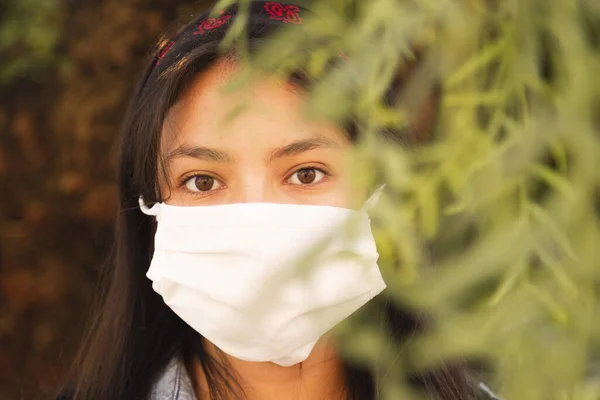 young woman wearing face mask on the street - Hispanic woman in nature wearing face mask