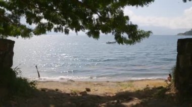 Ağaçların yanında küçük bir tekne, mavi gökyüzü ve Atitln, Guatemala 'daki volkanların ve dağların manzarası.