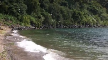 Guatemala 'nın Atitlan Gölü kıyıları, dağlar ve volkanlar arasında, deniz kıyısındaki karanlık kumlar, ağaçlar arasında