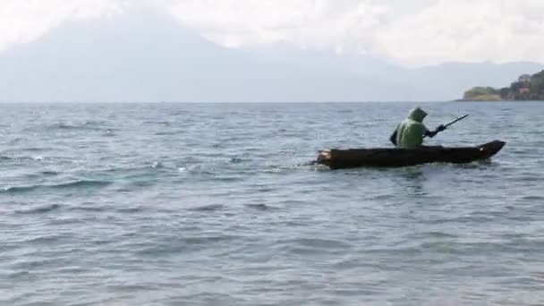 グアテマラのアッティルンの火山や山に囲まれた海岸に来る木製のモーターボートと湖 湖と青空の風景の中に小さなボートの男 — ストック動画