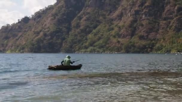 グアテマラのアティントンに木製のモーターボートがある湖 青い空の風景の中に小さなボートの男火山や山に囲まれて — ストック動画