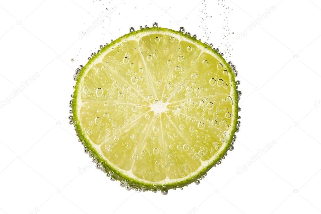 Slice of lime lemon in water with bubbles