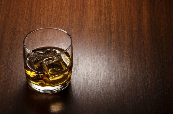 Bir bardak viski, kayaların üzerinde, kompozisyonun sol tarafında, ahşap arka planda izole edilmiş ve kırpma yolu ile