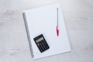 Hesap makinesi ve kalemi beyaz not defteri üzerinde