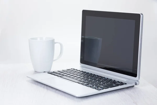 オープン ノート パソコンの横にあるコーヒー カップ — ストック写真
