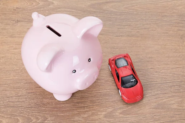 Pink piggy bank with red toy car